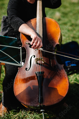 Cellist player hands. Violoncellist playing cello on background of field. Musical art, concept passion in music. Performance on nature. Close up of musical instruments. Shallow depth, vintage style. photo