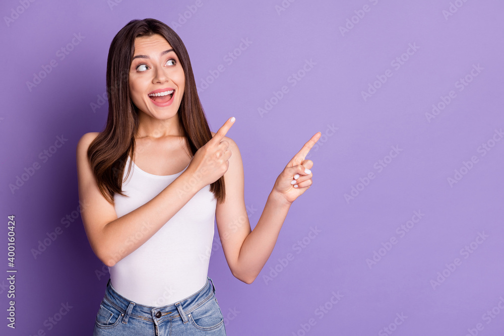 Photo of impressed shiny young woman wear casual white outfit looking pointing two fingers empty space isolated violet color background Photo of impressed shiny young woman wear casual white outfit looking pointing two fingers empty space isolated violet color background