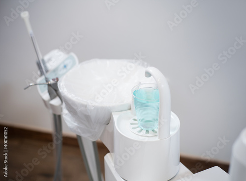 Cup of blue mouthwash in the dentist clinic. Dental mouthwash in a plastic cup near the dental chair for the patient