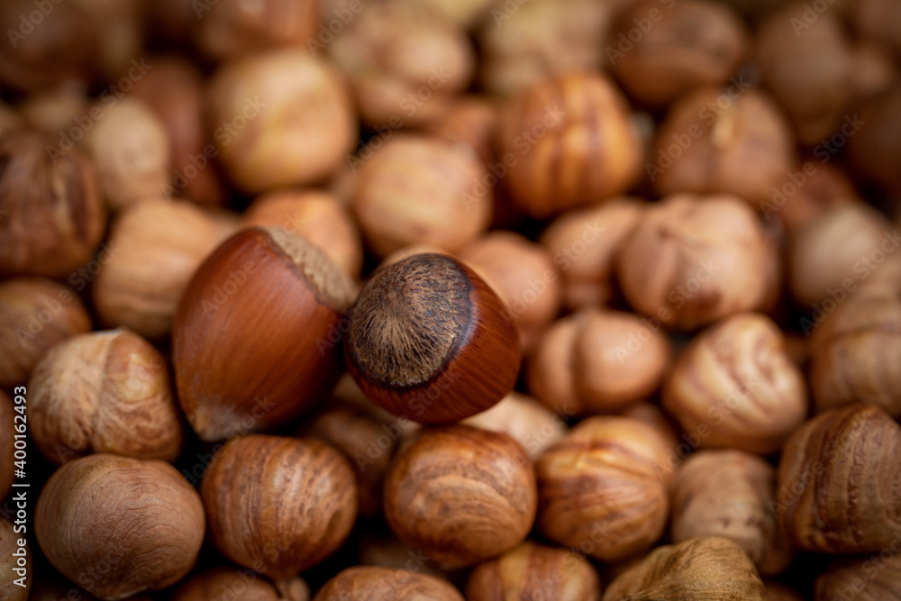 Two whole unpeeled hazelnuts and peeled nuts. Food background. Shallow depth of field Two whole unpeeled hazelnuts and peeled nuts. Food background. Shallow depth of field