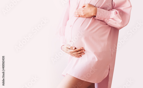 Pregnant woman holds hands on her belly. Pregnancy, maternity concept.