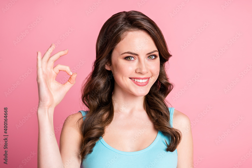 Portrait of optimistic cute brunette long hair style girl show okey sign wear blue top isolated on pink color background Portrait of optimistic cute brunette long hair style girl show okey sign wear blue top isolated on pink color background