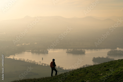 Male hiker looking at rolling landscape and hills of Czech Central Mountains at sunset photo