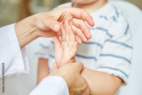 Osteopath behandelt Hand von Kind mit Verstauchung