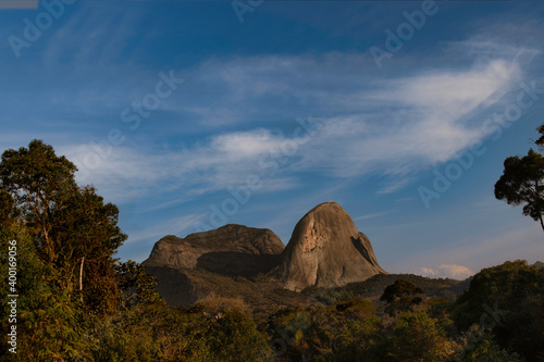 A rocky mountain lightened by the sunset under some clouds