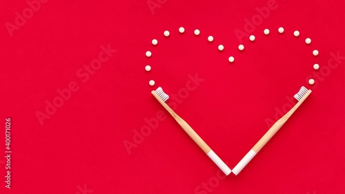 Bamboo toothbrushes and eco toothpaste in tablets. Creative heart on the red background. Valentines day concept. Plastic free, zero waste. photo