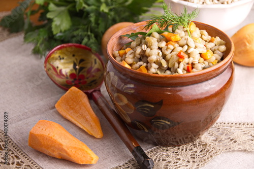 Pearl barley porridge stewed with vegetables onions carrots seasonings in a clay pot