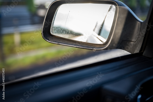 Car side mirror, view through dirty car window, reflection in the mirror. © PhotoRK