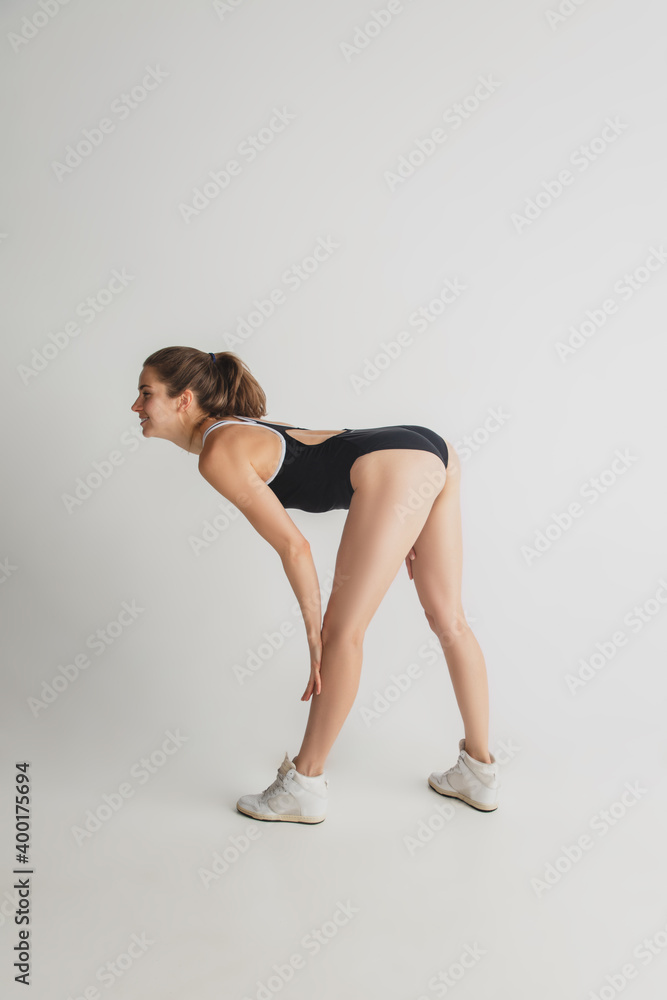 Attractive. Beautiful young woman's isolated on grey studio background. Having fun, happy, full length. Dancing, getting crazy mood, having fun. Stylish girl in black sportive swimsuit. Copyspace. Attractive. Beautiful young woman's isolated on grey studio background. Having fun, happy, full length. Dancing, getting crazy mood, having fun. Stylish girl in black sportive swimsuit. Copyspace.