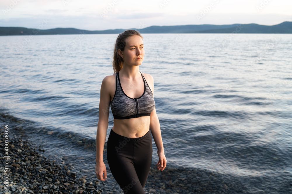 Sports girl walking along the lake at sunset Sports girl walking along the lake at sunset