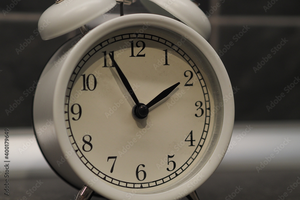 Round clock-alarm white on a gray background, isolated, close Round clock-alarm white on a gray background, isolated, close