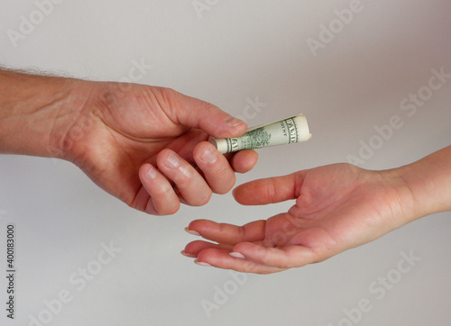 A man passes paper money American dollars to a woman. Paper money in hand. Close-up on hands on a light background.