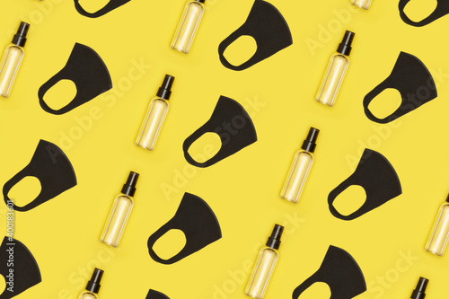 Black face mask and bottle with antiseptic on yellow Illuminating background pattern. High quality photo
