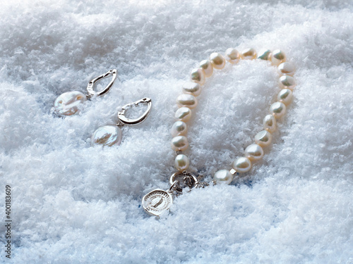 Luxury elegant baroque pearl earrings and bracelet with pendant on white snow background