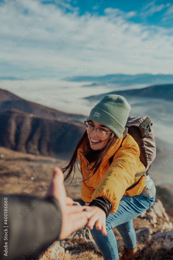 Naklejka premium People helping each other hike up a mountain at sunrise.