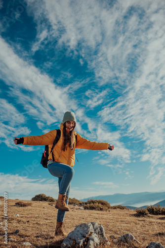 Cheering woman backpacker enjoy the view on sunrise mountain top cliff edge