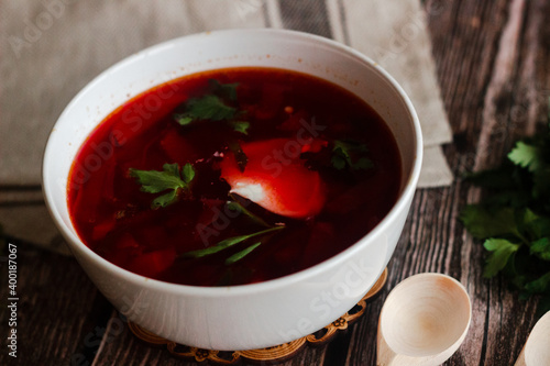 Borsch is a Russian national dish. Soup in a plate on a wooden table. Russian national cuisine. Borscht with sour cream and herbs