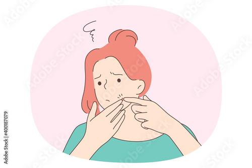 Squeezing pimples concept. Young unhappy frustrated girl standing trying to squeeze red acne spot pimple on her face. Problem skin dermatology concept 