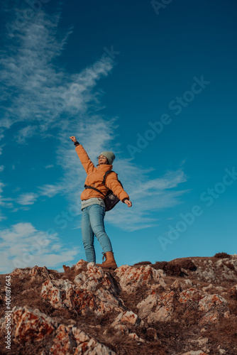 Cheering woman backpacker enjoy the view on sunrise mountain top cliff edge