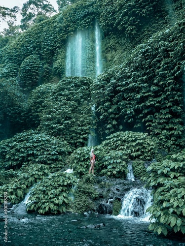 Woman standing at lush waterfalls in Lombok Indonesia