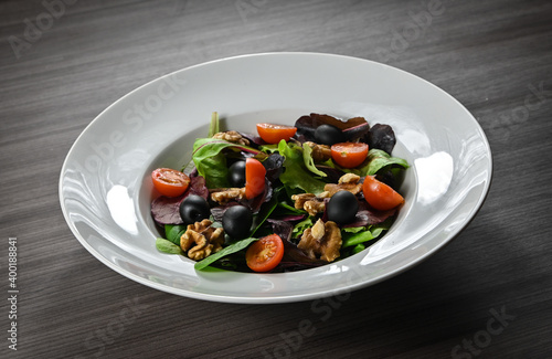 Delicious salad of cherry tomatoes, black olives, walnuts, assorted lettuce, sprouts, and fresh asparagus. Gourmet salad.