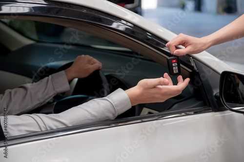 Close up hand of car rental agency giving car key to customer hand in side car.