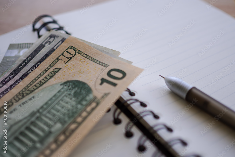 10 dollars on book with pen.  Business and financial for money saving concept.