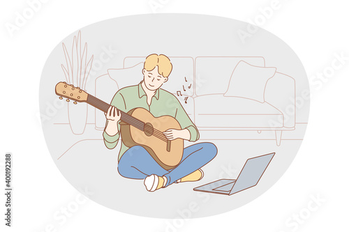 Music, playing guitar concept. Young boy sitting at home with guitar and learning to play online during distant lesson. Music festival, melody, song, hobby, entertainment, enjoy music 