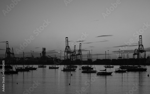 Backlit image of the harbor at dawn with many sailboats and large cranes, Las Palmas of Gran Canaria