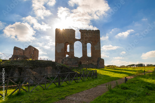 Villa dei Quintili, Rome, the thermal baths, a suggestive panoramic image of the brick construction of the calidarium at sunset with the sun rising from the ruins and the blue sky and clouds. photo