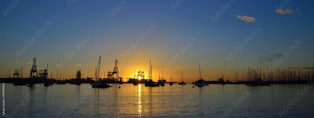Sporting and commercial ports at sunrise with many sailboats, cranes and blue sky, Las Palmas of Gran Canaria