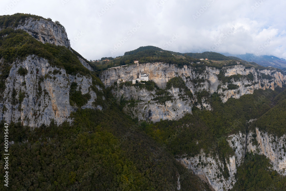 Aerial view of the church on the sheer cliff. The unique Sanctuary Madonna della Corona church in the rock. The sanctuary is high in the mountains of Italy. Italian church at high altitude in the Alps
