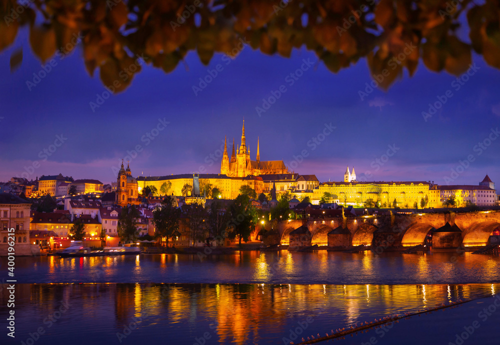 colorful panorama of the night city. Fabolous art photography of Prague. Czech Republic. Architecture, bridge, lights are reflected in water. Yellow leaves of trees. Warm autumn nature view. Nobody