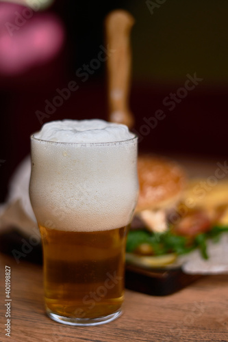 A glass of beer with foam and a burger