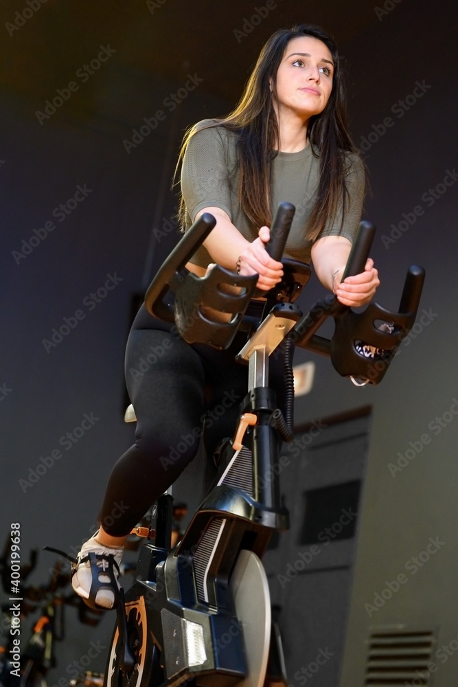 Naklejka premium Woman in gym spinning on fitness bike. High quality photo
