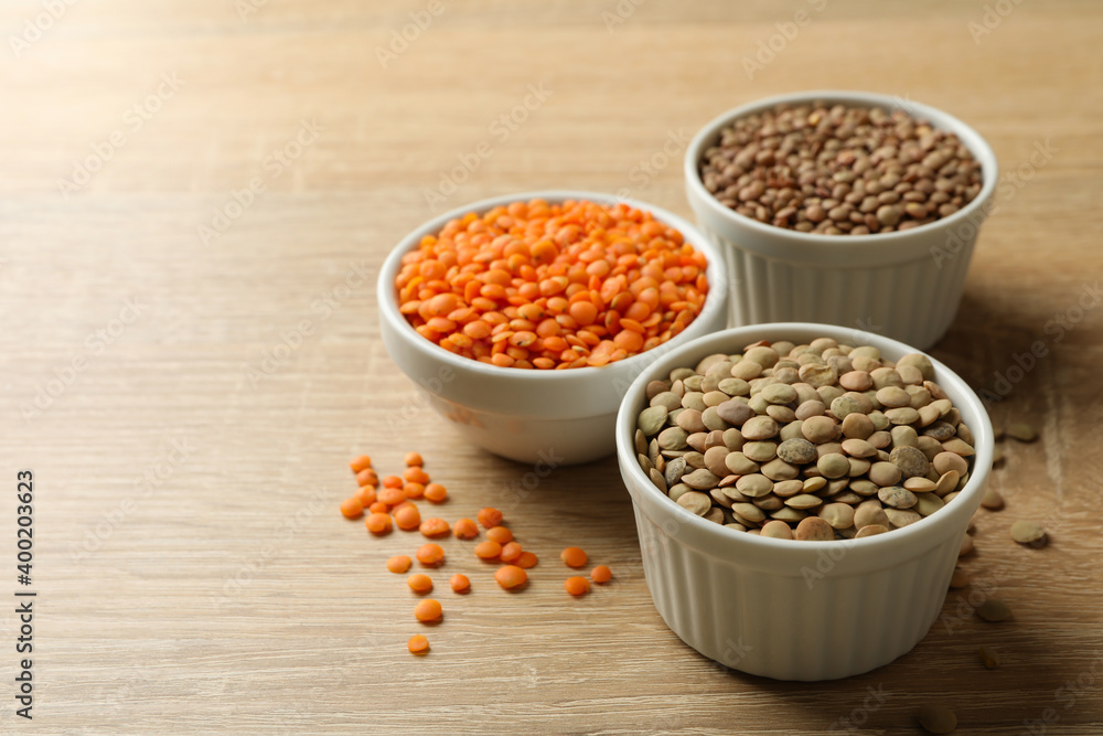 Bowls with different legumes on wooden background, space for text Bowls with different legumes on wooden background, space for text