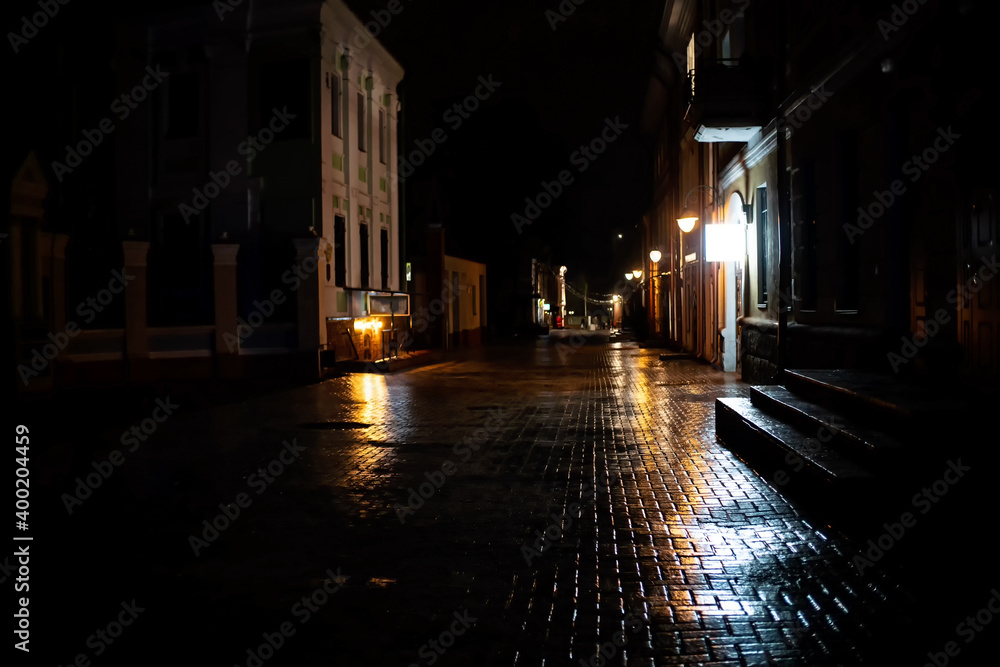 Night view of the city street with a brick road covered with ice, rain. Concept of an unsafe road for pedestr Night view of the city street with a brick road covered with ice, rain. Concept of an unsafe road for pedestr