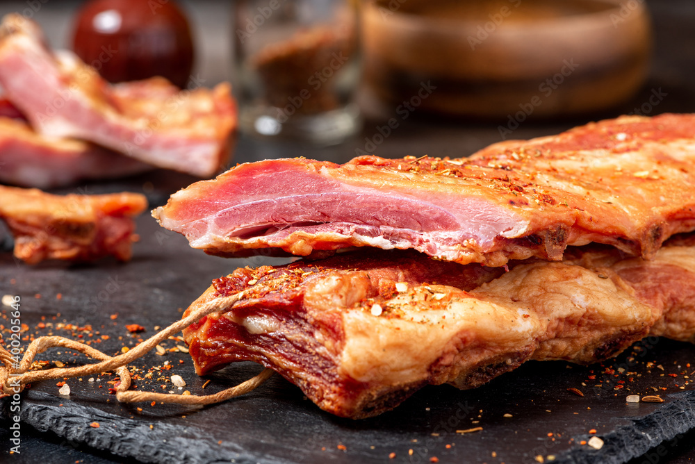 Dried pork ribs close-up on a dark table. Sliced jerky pork meat.