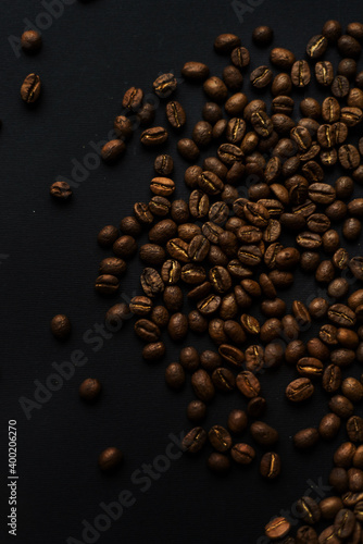 Close up of brown coffee beans in natural light on black table  black background in a dark theme. Moody picture with shadows. Sun rays.