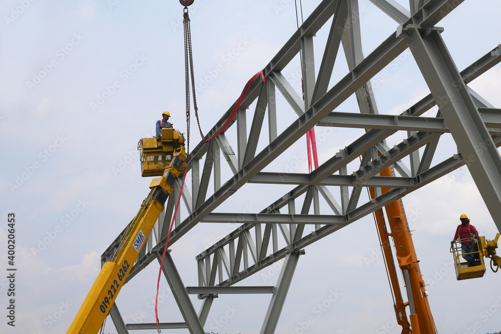 MALACCA, MALAYSIA -MARCH 12, 2020: Construction workers working at height at the construction site. They are supplied with harnesses and other safety equipment to prevent them from having an accident. MALACCA, MALAYSIA -MARCH 12, 2020: Construction workers working at height at the construction site. They are supplied with harnesses and other safety equipment to prevent them from having an accident.