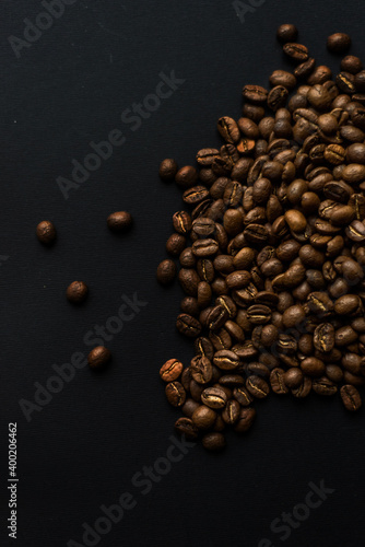 Close up of brown coffee beans in natural light on black table  black background in a dark theme. Moody picture with shadows. Sun rays.