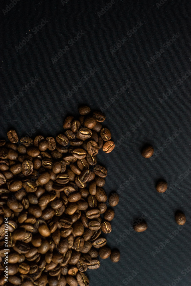 Close up of brown coffee beans in natural light on black table, black background in a dark theme. Moody picture with shadows. Sun rays. Close up of brown coffee beans in natural light on black table, black background in a dark theme. Moody picture with shadows. Sun rays.