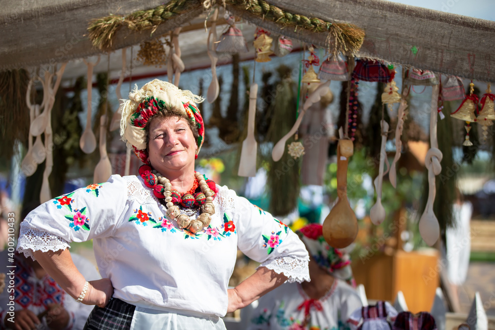 Obraz premium Ukrainian woman in embroidered shirt against a rustic background. Slavic clothing.