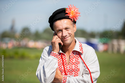 An elderly Slavic man in an embroidered shirt speaks on the phone. photo