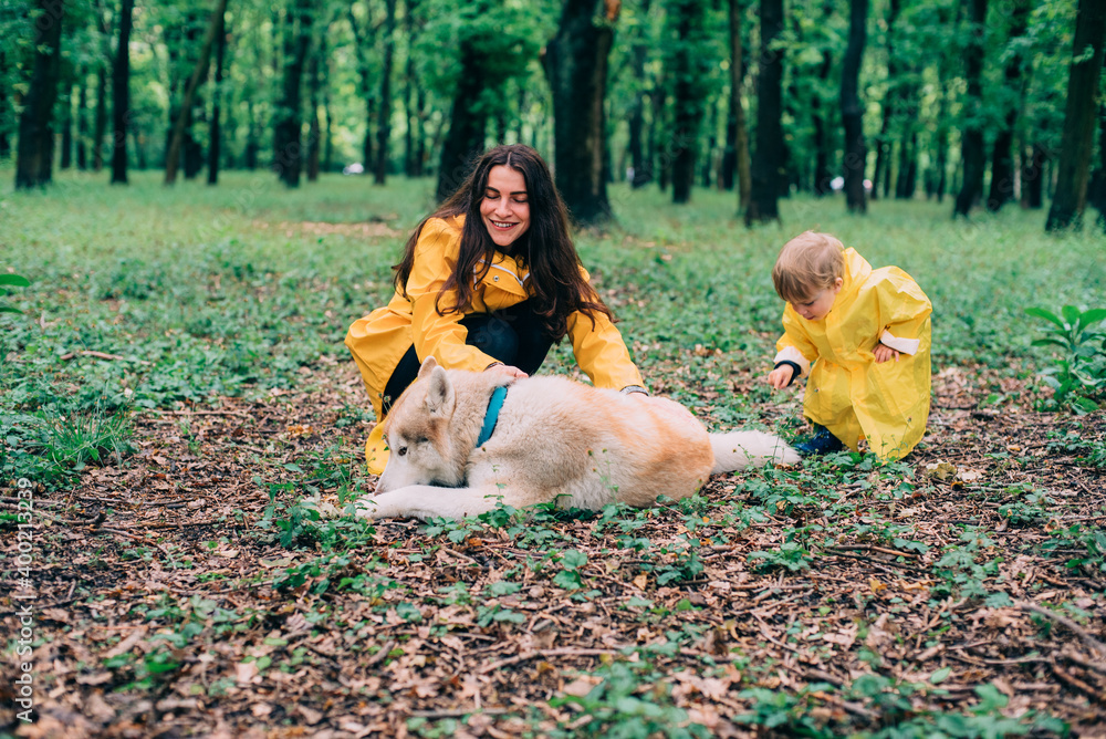 young mother with her son in yellow rain jackets playing outdoors in park after the rain. Family in park playing together and having fun. young mother with her son in yellow rain jackets playing outdoors in park after the rain. Family in park playing together and having fun.