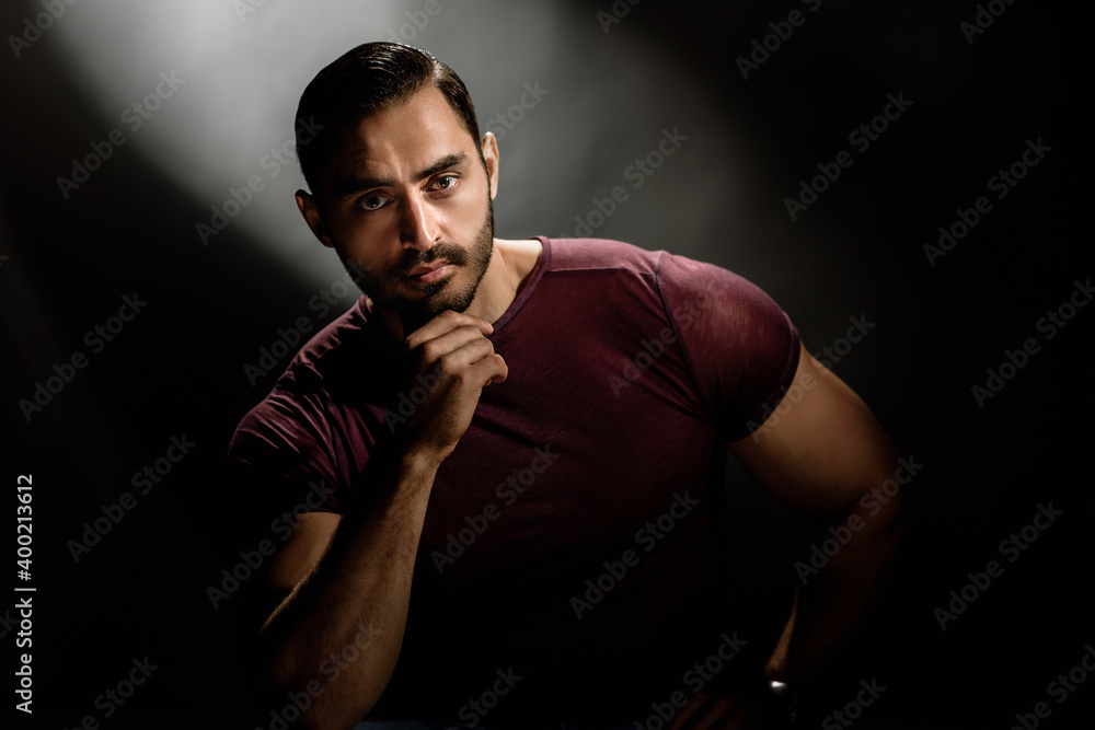 Fashionable brutal bearded man posing on black background