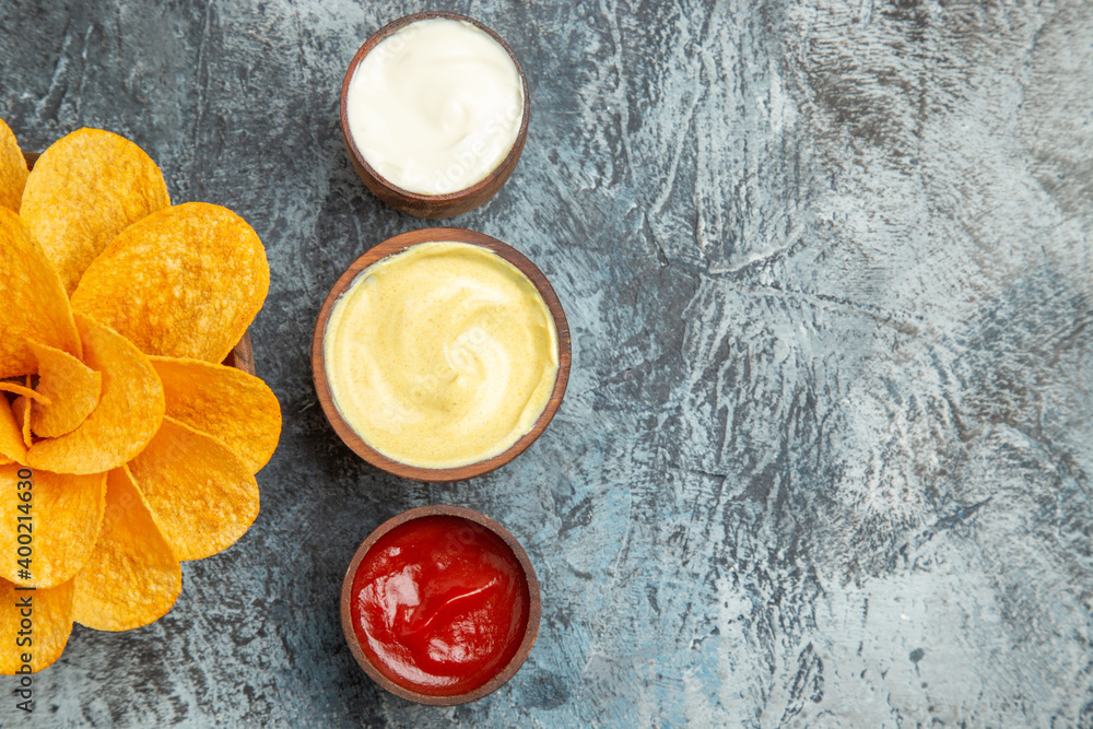 Half shot of homemade potato chips decorated like flower shaped and salt with ketchup mayonnaise on gray background Half shot of homemade potato chips decorated like flower shaped and salt with ketchup mayonnaise on gray background