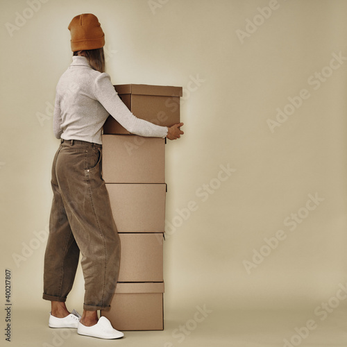 Girl near a stack of cardboard boxes. Archive storage. Moving and packaging, environmentally friendly materials.