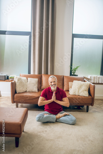 Grey-haired man sitting on the floor and doing yoga
