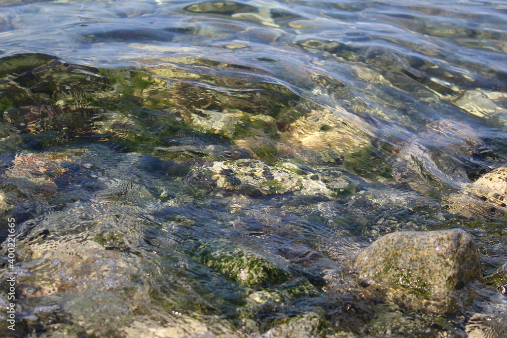 large stones with green algae under the clear transparent water of the sea 